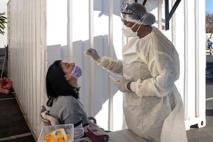 A woman receives a nasal swab, from a health worker wearing personal protective equipment (PPE), to be tested for COVID-19 at the Fourways Life Hospital in Johannesburg on June 28, 2021. - South Africa's President Cyril Ramaphosa on June 27, 2021 reimposed restrictions for two weeks to combat a surge in the highly contagious coronavirus Delta variant.
He banned all gatherings, except for funerals where numbers will be capped at 50, and also ordered a ban on the sale of alcohol.
Eateries and restaurants will not be allowed to serve sit-down meals, and will only be allowed to sell food for take-away or delivery. 
A nighttime curfew has been lengthened by an hour - starting at 9pm till 4am. (Photo by Emmanuel Croset / AFP)