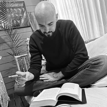 Abel Pintos fuma un habano mientras lee un libro, una acción que fue criticada por sus seguidores en Instagram