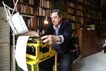 Abel Posse en su escritorio; detrás, la biblioteca personal, de unos cinco mil ejemplares