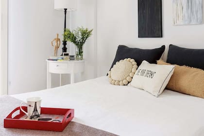 Acolchado (Zara Home). Almohadones: grises tejidos a mano, circular con pompones y de yute de 70x30cm (todo de Tienda de Costumbres). En la cabecera, dúo de cuadros pintados por la madre de Pilar.