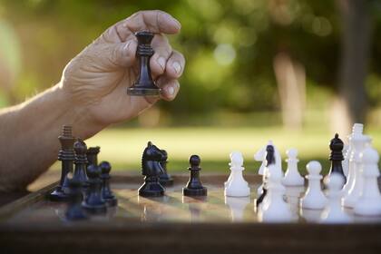 Active retired persons, hand of old man holding chess piece in park. Closeup shot, copy space
