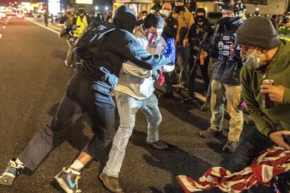 Activistas de Black Lives Matter chocan con un manifestante de derecha después de que la multitud intentara quemar una bandera estadounidense en Washington