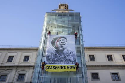 Activistas de Greenpeace cuelgan una ilustración del artista Shepard Fairey en la fachada del museo Reina Sofía con una imagen tomada por el fotoperiodista de Gaza, Belal Khaled (AP Photo/Bernat Armangue)
