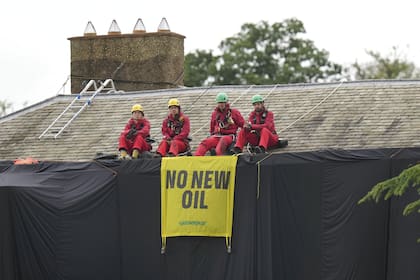 Activistas de Greenpeace se sientan en el techo de la casa del primer ministro británico Rishi Sunak en Richmond, North Yorkshire, Inglaterra, después de cubrirla con tela negra, el jueves 3 de agosto de 2023.
