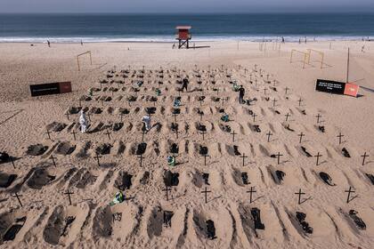 Activistas de la ONG brasileña Río de Paz cavan tumbas simuladas en la playa de Copacabana, Río de Janeiro, como protesta contra el mal manejo de la pandemia en Brasil