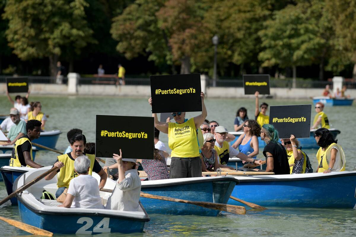 Activistas viajan en botes con carteles que dicen "¡Puerto seguro ahora!" en el Parque del Retiro de Madrid el 20 de agosto de 2019 durante una campaña de sensibilización organizada por Amnistía Internacional en apoyo al barco humanitario Open Arms