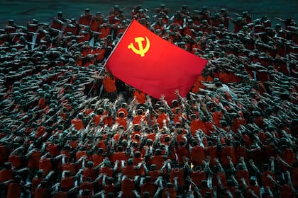 Actores caracterizados como rescatistas rodean una bandera del Partido Comunista durante una gala antes del 100 aniversario de la fundación de la formación, en Beijing, el 28 de junio de 2021. (AP Foto/Ng Han Guan)