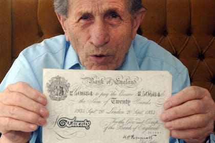 Adolf Burger, uno de los prisioneros encargados de imprimir los billetes falsos en Sachsenhausen, muestra un billete de 20 libras