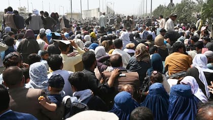 Afganos se congregan en una carretera cerca de la parte militar del aeropuerto de Kabul el 20 de agosto de 2021