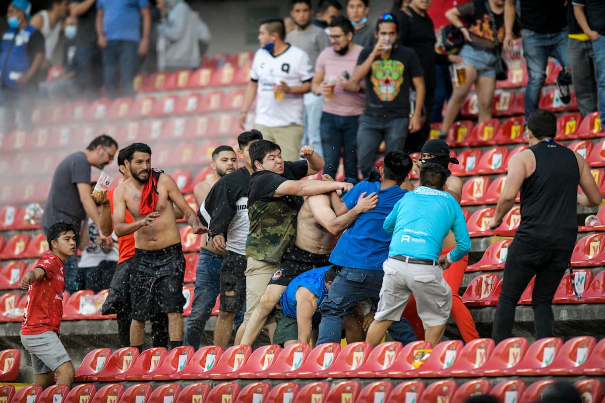 Aficionados chocan durante un partido de la liga mexicana de fútbol entre el anfitrión Querétaro y Atlas de Guadalajara, en el estadio Corregidora, en Querétaro, México, el sábado 5 de marzo de 2022.