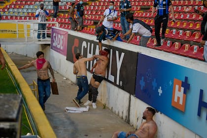 Aficionados chocan durante un partido de la liga mexicana de fútbol entre el anfitrión Querétaro y Atlas de Guadalajara, en el estadio Corregidora, en Querétaro, México, el sábado 5 de marzo de 2022.