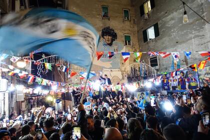 Aficionados de Argentina se reúnen bajo un mural de la difunta leyenda del fútbol argentino Diego Maradona mientras celebran la victoria en el Mundial de Qatar 2022 contra Francia en Nápoles el 18 de diciembre de 2022.