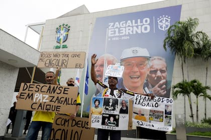 Aficionados del exjugador y seleccionador de Brasil Mario Zagallo sostienen pancartas afuera de las instalaciones de la Confederación de Brasil en donde se realiza el fúneral de Zagallo el domingo 7 de enero del 2024. (AP Foto/Bruna Prado)