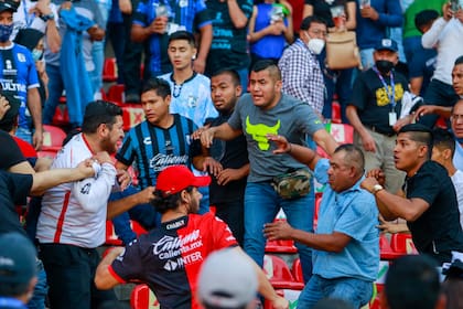 Aficionados del Querétaro y del Atlas riñen durante un partido de la Liga MX, disputado el sábado 5 de marzo de 2022, en el Estadio Corregidora (AP Foto/Eduardo Gomez Reyna)