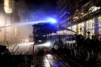 Agentes de la policía italianos utilizan un cañón de agua durante una protesta de activistas de extrema derecha contra las medidas de restricción del gobierno para frenar la propagación del coronavirus, en el centro de Turín, el 26 de octubre de 2020