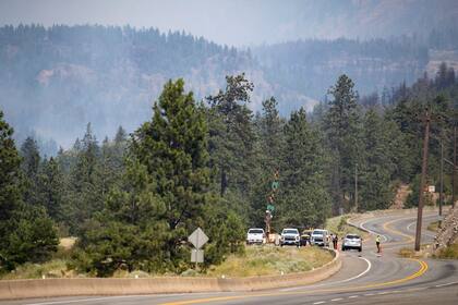 Agentes de la Real Policía Montada de Canadá manejan un bloqueo carretero en la autopista transcanadiense debido a un incendio forestal, el viernes 2 de julio de 2021 en Lytton, Columbia Británica. (Darryl Dyck/The Canadian Press via AP)