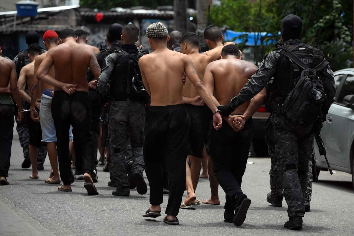 Agentes de policía escoltan a sospechosos arrestados durante la Operación Contención fuera de la favela Vila Cruzeiro, en el complejo Penha, Río de Janeiro, Brasil