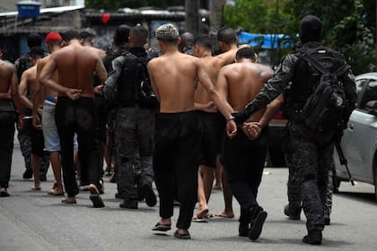 Agentes de policía escoltan a sospechosos arrestados durante la Operación Contención fuera de la favela Vila Cruzeiro, en el complejo Penha, Río de Janeiro, Brasil