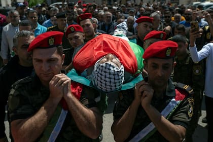 Agentes de seguridad palestinos trasladan el cuerpo de Muhammad Assaf durante su entierro en al aldea cisjordana de Kufr Laqef, cerca de Qalqiliya, el 13 de abril de 2022. (AP Foto/Nasser Nasser)