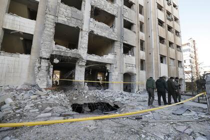 Agentes de seguridad sirios inspeccionan el domingo 19 de febrero de 2023 los daños en un barrio residencial después de un ataque aéreo israelí a Damasco, la ciudad capital de Siria. (AP Foto/Omar Sanadiki)