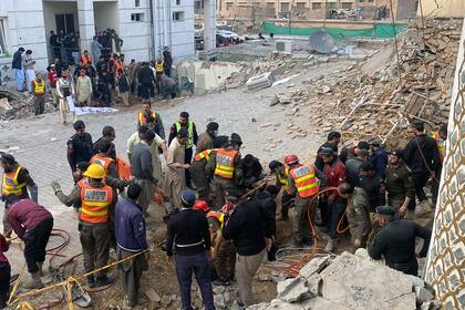 Agentes de seguridad y rescatistas buscan cuerpos en el lugar de un ataque suicida en Peshawar, Pakistán, el lunes 30 de enero de 2023. Decenas de personas murieron y más de un centenar resultaron heridas en la explosión en una mezquita. (AP Foto/Zubair Khan)