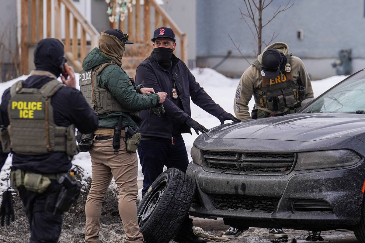 Agentes federales cambian el neumático de un vehículo durante una redada migratoria en Minneapolis. (AP Foto/Ryan Murphy)