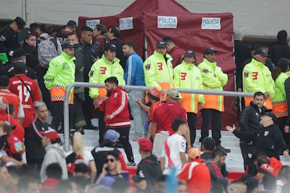 Agentes policiales y empleados de seguridad resguardan la zona donde falleció un espectador, al caer desde la tribuna durante el partido de River contra Defensa y Justicia