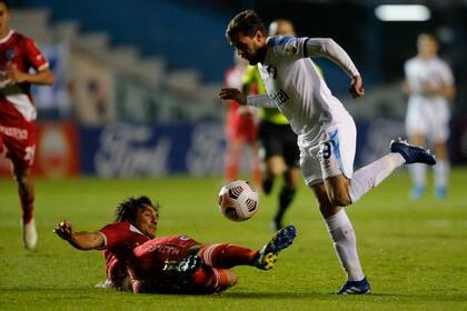 Agustín Oliveros, de Nacional, busca escaparse; Kevin Mac Allister lo marca desde el piso