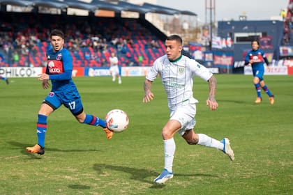 Agustín Urzi, wing de Banfield, se lleva la pelota ante la marca de Lucas Blondel