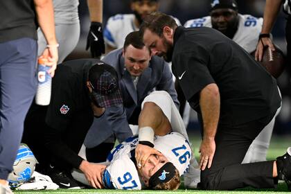 Aidan Hutchinson (97), defensive end de los Lions de Detroit, es atendido por el personal médico del equipo después de sufrir una lesión, aparentemente una fractura, durante la segunda mitad del juego de la NFL en contra de los Cowboys de Dallas, el domingo 13 de octubre de 2024, en Arlington, Texas. (AP Foto/Jerome Miron)