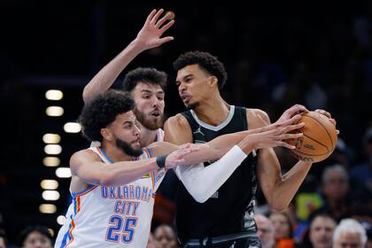 Ajay Mitchell (25), de los Thunder de Oklahoma City, intenta robarle el balón a Victor Wembanyama, derecha, de los Spurs de San Antonio, mientras Chet Holmgren, centro, presiona durante la segunda mitad del juego de baloncesto de la NBA, el miércoles 30 de octubre de 2024, en Oklahoma City. (AP Foto/Nate Billings)