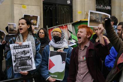 Los manifestantes sostienen carteles que dicen "desmantelar las fronteras coloniales" mientras los estudiantes ocupan un edificio de Sciences Po  en apoyo de los palestinos, en París el 26 de abril de 2024