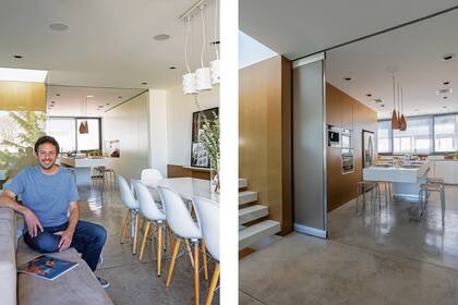El arquitecto Abramzon junto al comedor, que está en línea con la cocina y continúa la combinación de blanco y madera sobre la base gris.