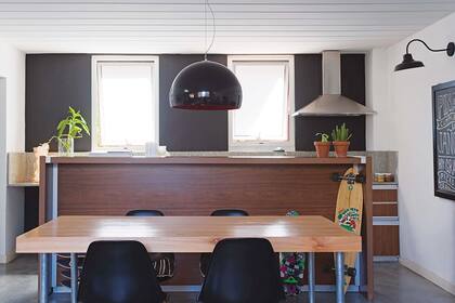 Al fondo, la pared de la cocina está pintada en gris oscuro