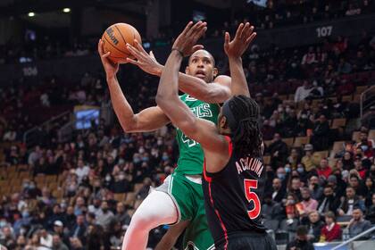 Al Horford de los Celtics de Boston salta para anotar mientras lo defiende Precious Achiuwa de los Raptors de Toronto en el encuentro del domingo 28 de noviembre del 2021. (Chris Young/The Canadian Press via AP)