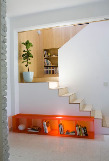Al pie de la escalera, biblioteca de acrílico, obra de Juju Estudio. Artefactos de iluminación de pared ‘Escolar’ (Serconel Iluminación).