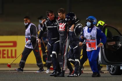 Alan van der Merwe traslada a Romain Grosjean, junto al doctor Ian Roberts (casco), tras el espeluznante accidente que el suizo-francés protagonizó en el Gran Premio de Bahrein 2020; el piloto del Auto Médico, por su condición de antivacunas, se ausentará del desenlace del campeonato de Fórmula 1