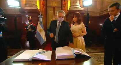 Alberto Fernández firma el libro de actas ante la atenta mirada de Cristina Kirchner