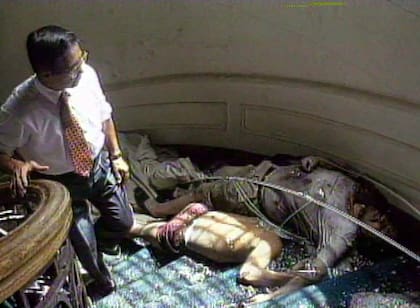 Alberto Fujimori camina la escena luego de que terminara la batalla; atrás suyo, los cuerpos de dos guerrilleros