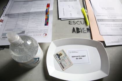 Alcohol en gel y bandeja de plástico para el documento en una de las mesas de la escuela de Juncal 3131