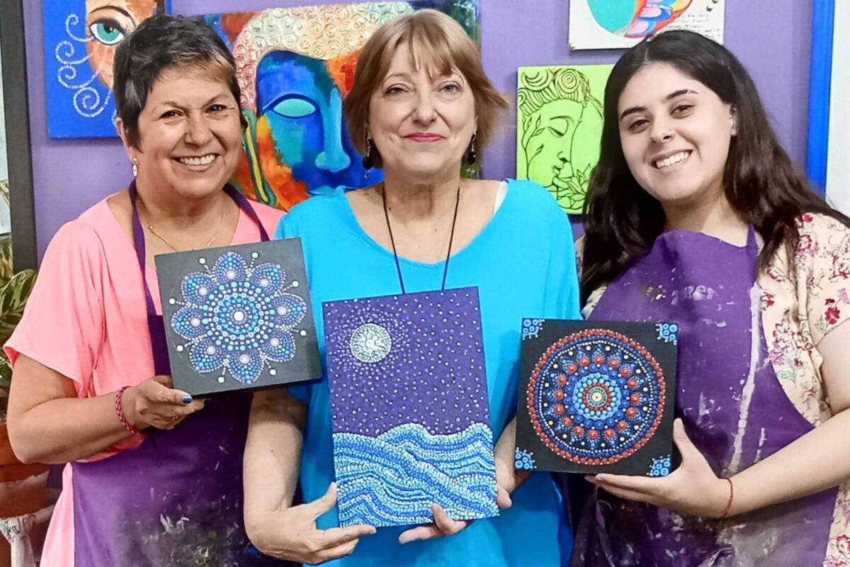 Alejandra, en el centro, en una clase de pintura con su profesora y una compañera.