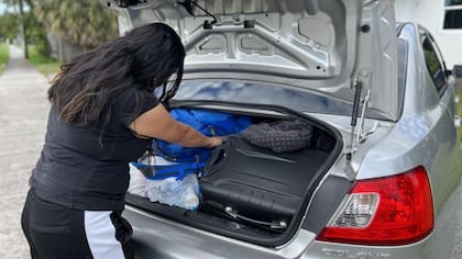 Alejandra intenta hacer espacio en el auto para los juguetes de los niños