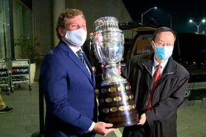 Alejandro Domínguez, presidente de la Conmebol, exhibe la Copa América junto a una autoridad de Sinopharm, el laboratorio chino que proveyó vacunas para la organización del torneo