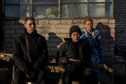Alesha Babenko, de 27 años (izquierda); Vitaliy Mysharskiy, de 14 (centro) y una integrante de la familia, Tanya Babii, en el patio de la casa de la familia en el pueblo ucraniano recientemente liberado de Kyselivka, en las afueras de Jersón, el martes 15 de noviembre de 2022. A medida que la violencia se intensifica en Ucrania, los abusos perpetrados por las tropas rusas contra los derechos humanos se generalizan, según Naciones Unidas. (AP Foto/Bernat Armangue)