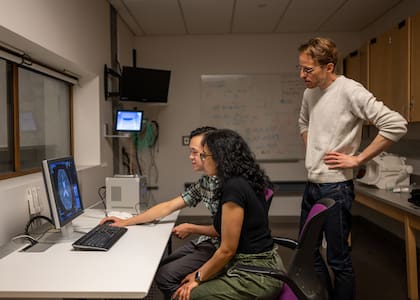 Alex Huth (de pie), Jerry Tang y Shailee Jain (sentados), los investigadores detrás del desarrollo que permite leer y transcribir el pensamiento de una persona
Un descodificador creado en la universidad de Texas y basado en GPT lee los pensamientos registrados por un escáner cerebral. El sistema capta el sentido de las frases más que su literalidad gracias a la inteligencia artificial