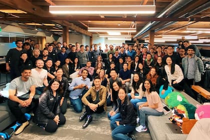 Alexandr Wang (centro, sentado), junto al equipo de su compañía, Scale AI