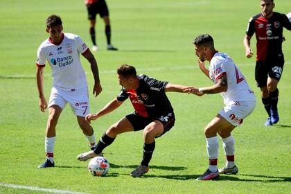 Alexis Rodríguez intenta dominar la pelota ante las marcas de Erquiaga y Garro (7); a Newell's se le escapó el triunfo sobre el final