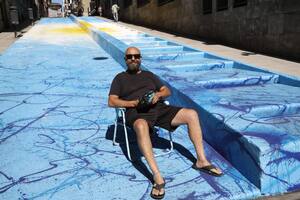 Alfredo Segatori sentado sobre su obra, el mural "Exabrupto de Color. Campeones del Mundo" sobre la escalera de la calle Lavalle, entre Leandro Alem y 25 de Mayo