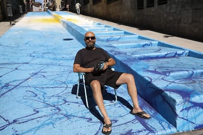 Alfredo Segatori sentado sobre su obra, el mural "Exabrupto de Color. Campeones del Mundo" sobre la escalera de la calle Lavalle, entre Leandro Alem y 25 de Mayo