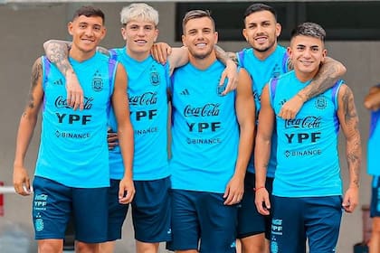 Algunos chicos con jugadores de la generación intermedia: Alejandro Garnacho (segundo) y Thiago Almada (quinto) sonríen con Nahuel Molina Lucero, Giovani Lo Celso y Leandro Paredes, en una práctica de la selección argentina en Pekín.